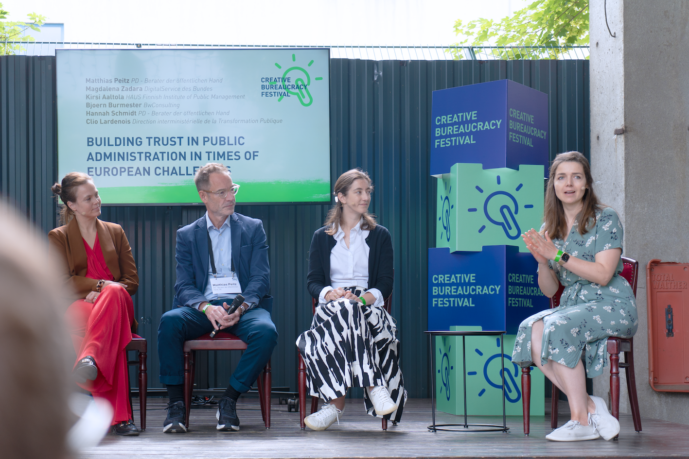 Teilnehmende eines Panels sitzen gemeinsam auf der Bühne des Creative Bureaucracy Festivals