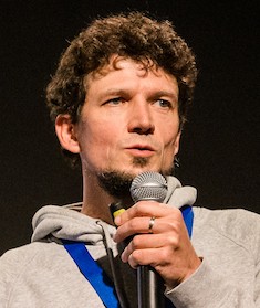 A photo of Fabian Klenk speaking into a microphone