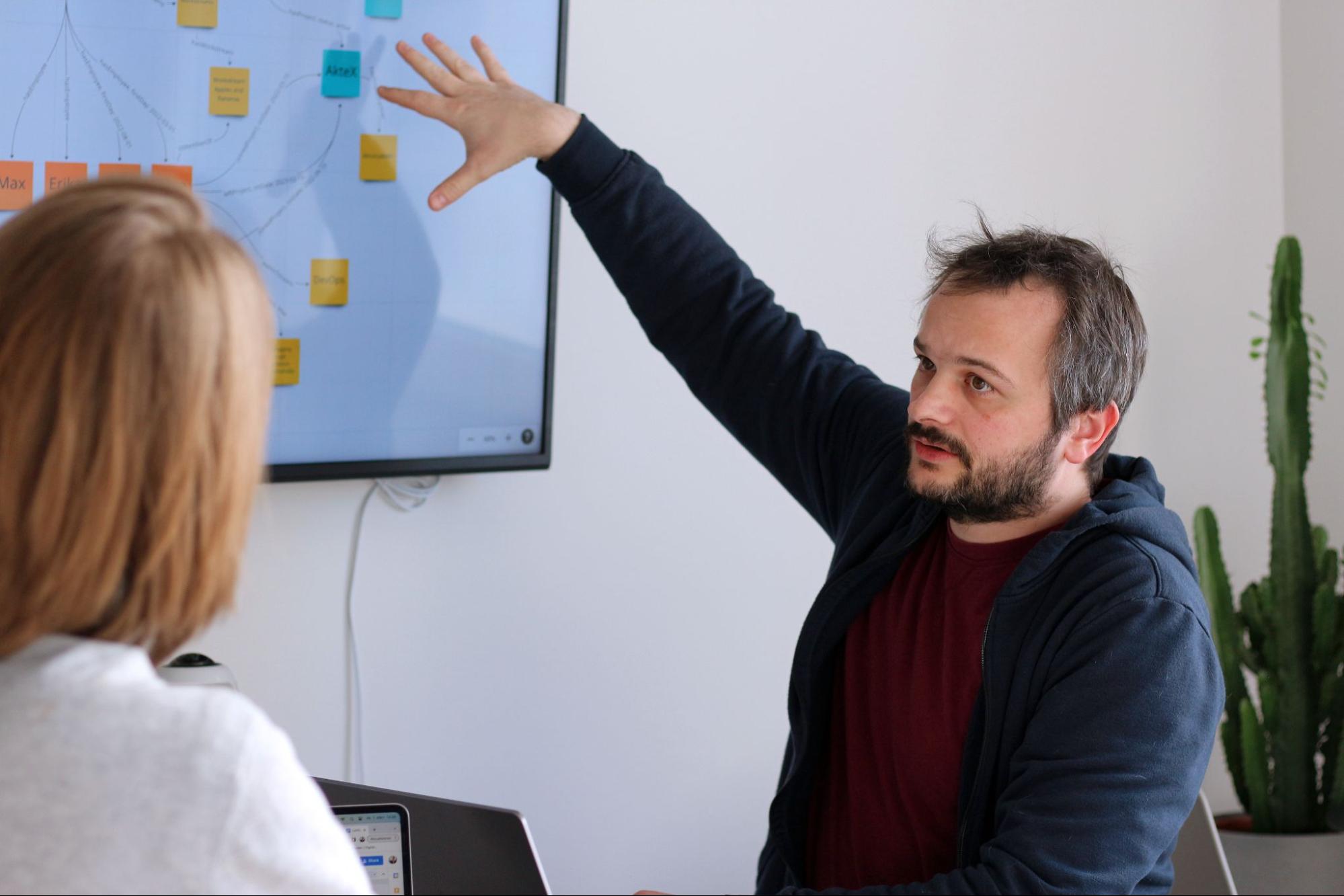 Benjamin erklärt dem ihm gegenüber sitzenden Interviewer die Bedeutung einer Grafik, welche die Zusammenhänge eines Wissensgraphens visualisert