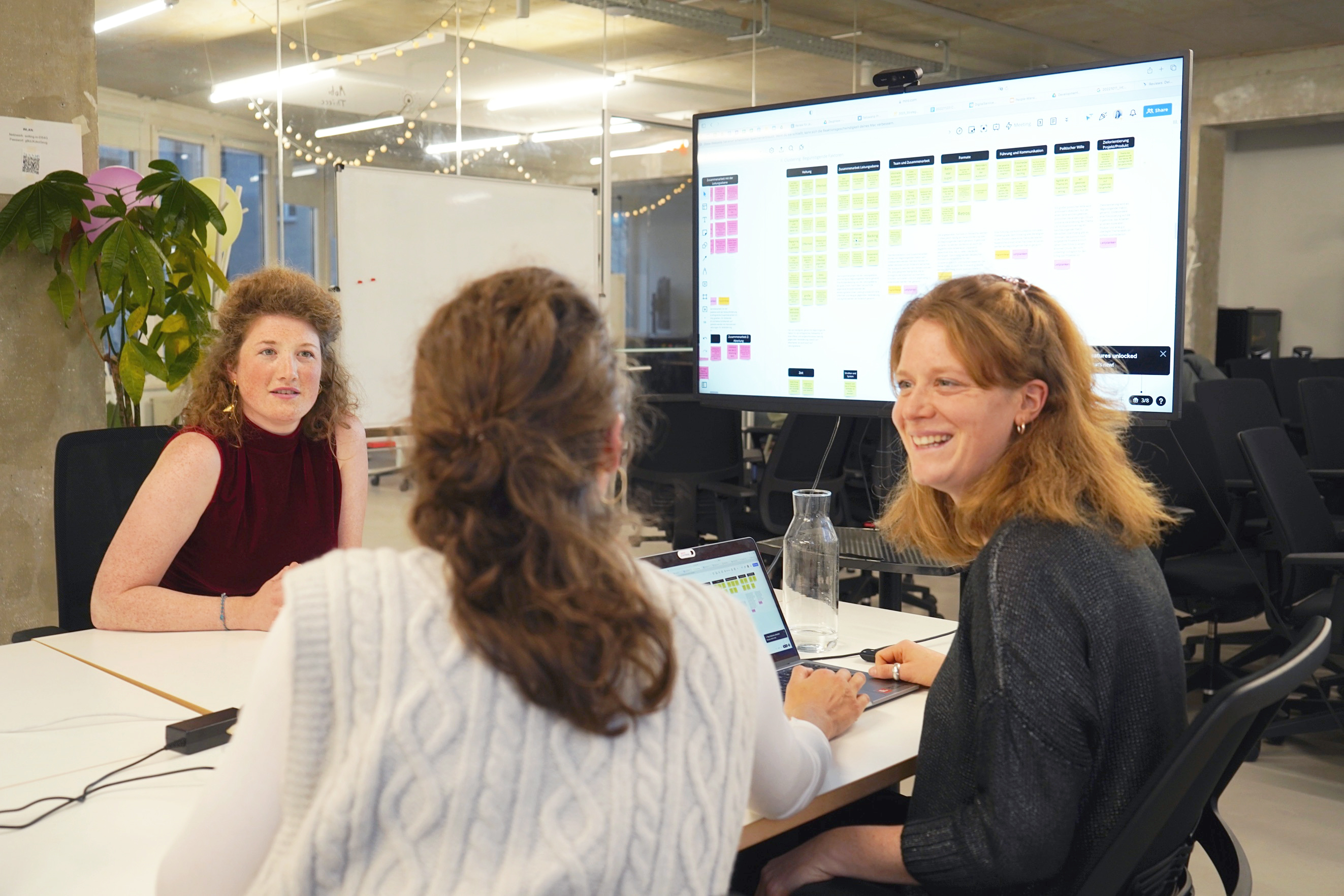 Drei Kolleginnen des Fellowship-Teams sitzen gemeinsam an einem Tisch im Rahmen des Auswahverfahrens für Fellows und beraten sich