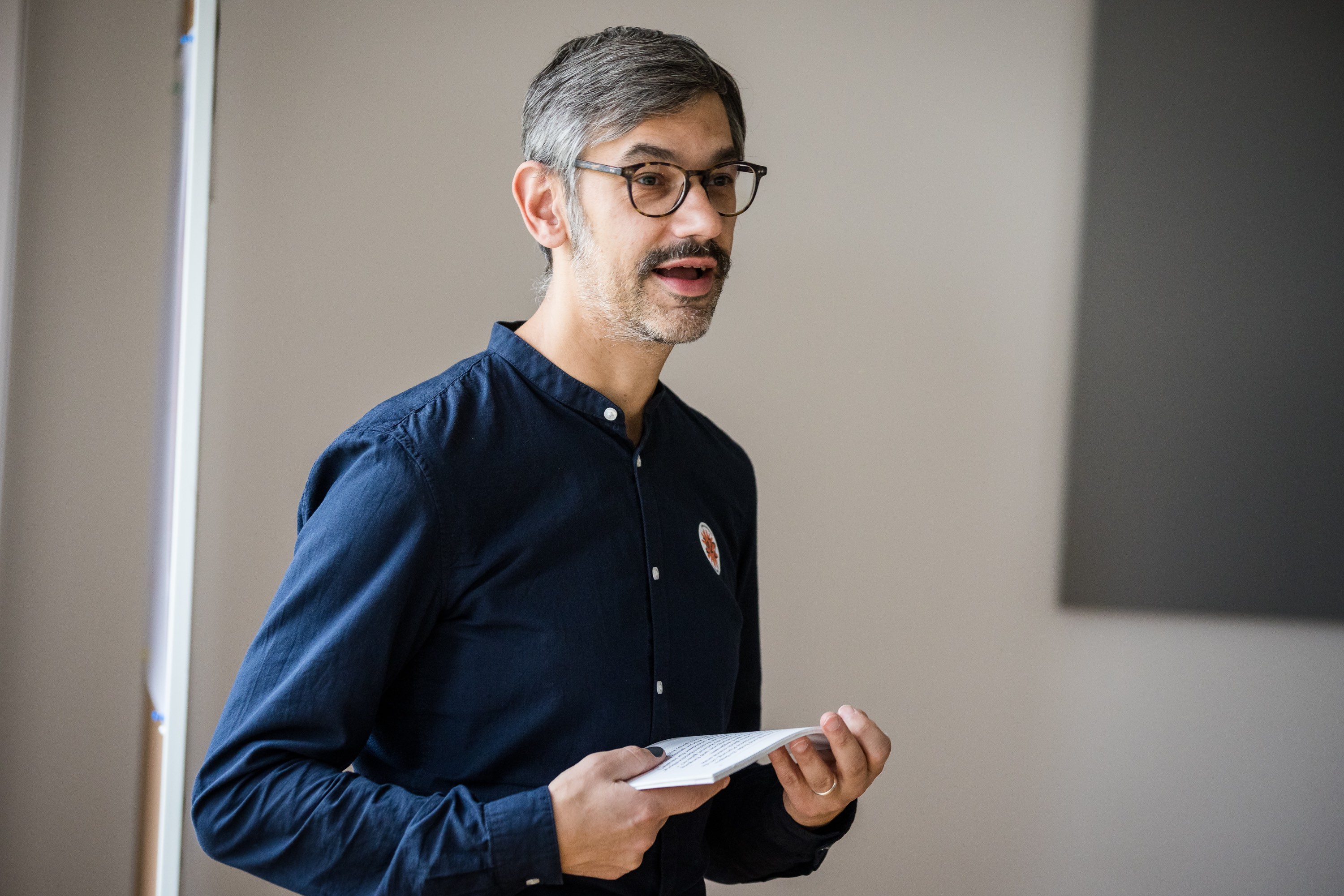 Nahaufnahme von Christian Müller bei einer Präsentation. Er hält dabei Moderationskarten.