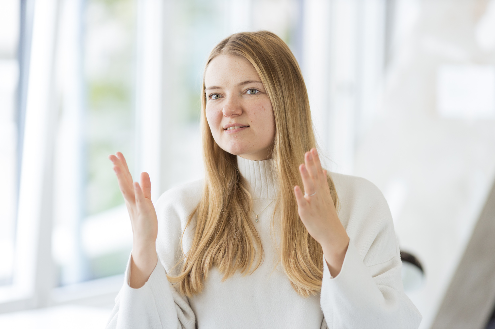 Carolin hat beide Hände auf Schulterhöhe, die Handflächen sind zueinander egrichtet und sie blickt geradeaus.