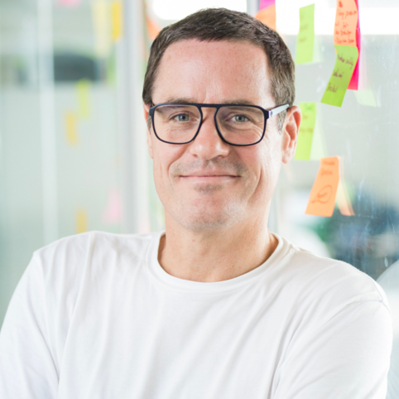 Software developer Klaus in portrait. Klaus wears glasses and a white T-shirt.