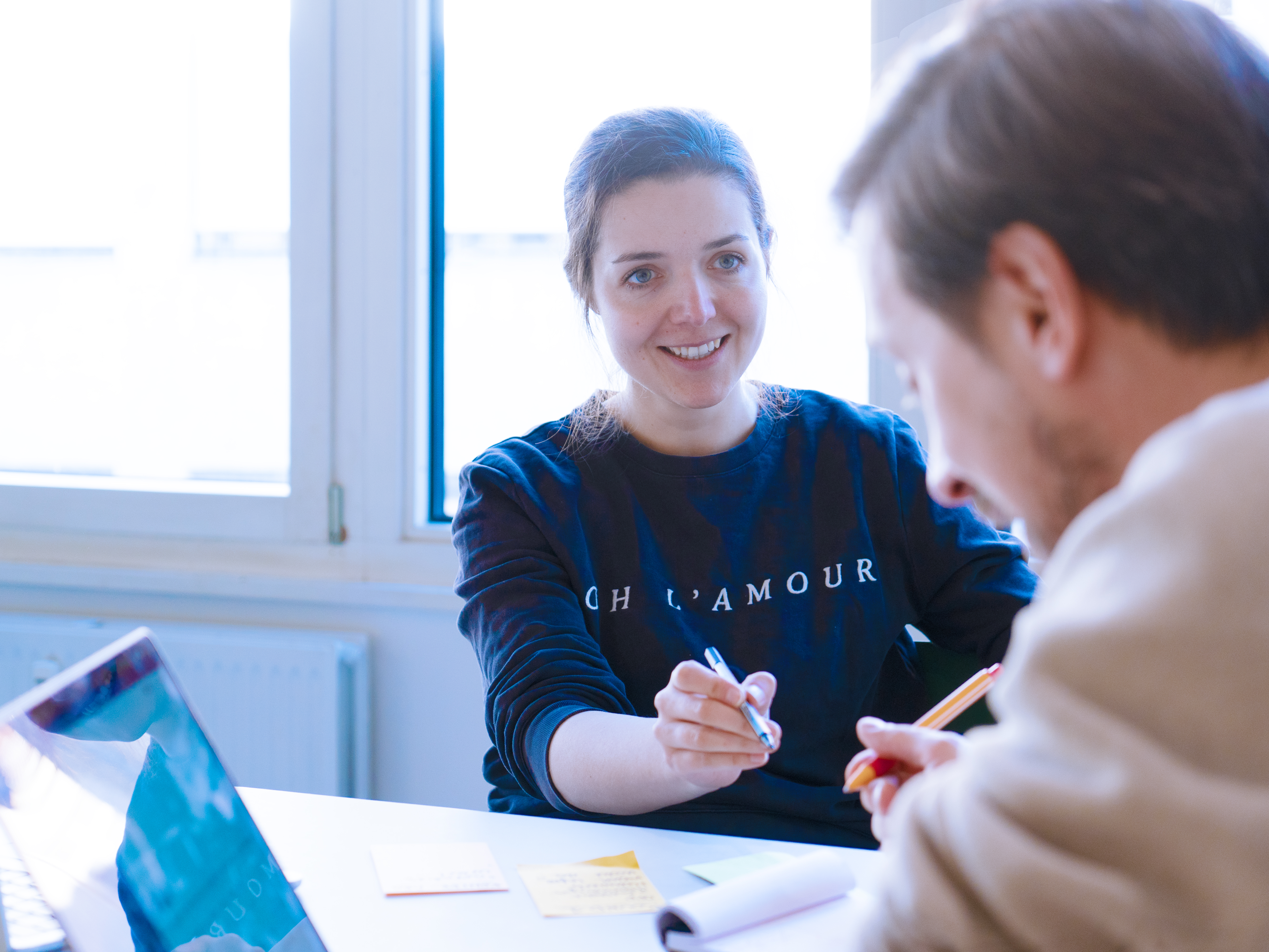 Foto von Magdalena Zadara im Gespräch mit Niko Felger. Beide sitzen an einem Schreibtisch in einem modernen Büroraum.