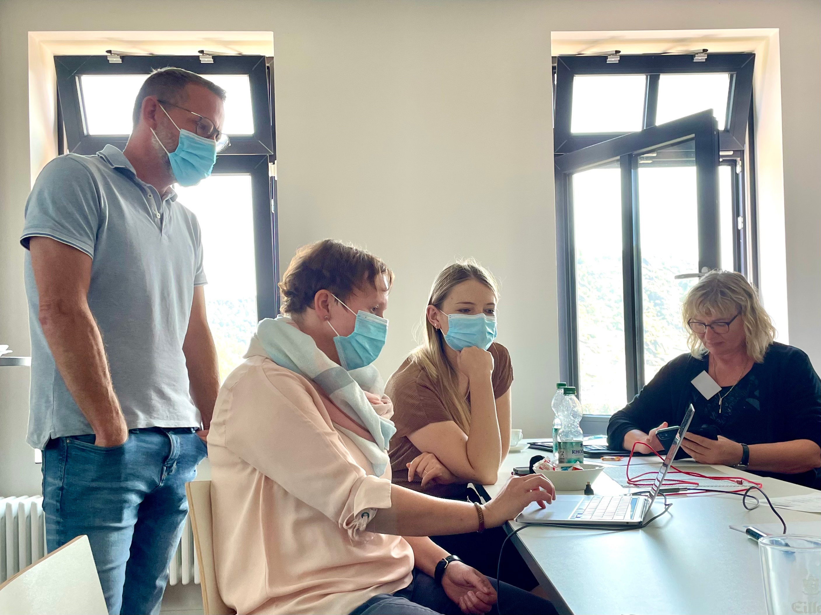 Schulung von Mitarbeitenden an einem Laptop in einem Büro