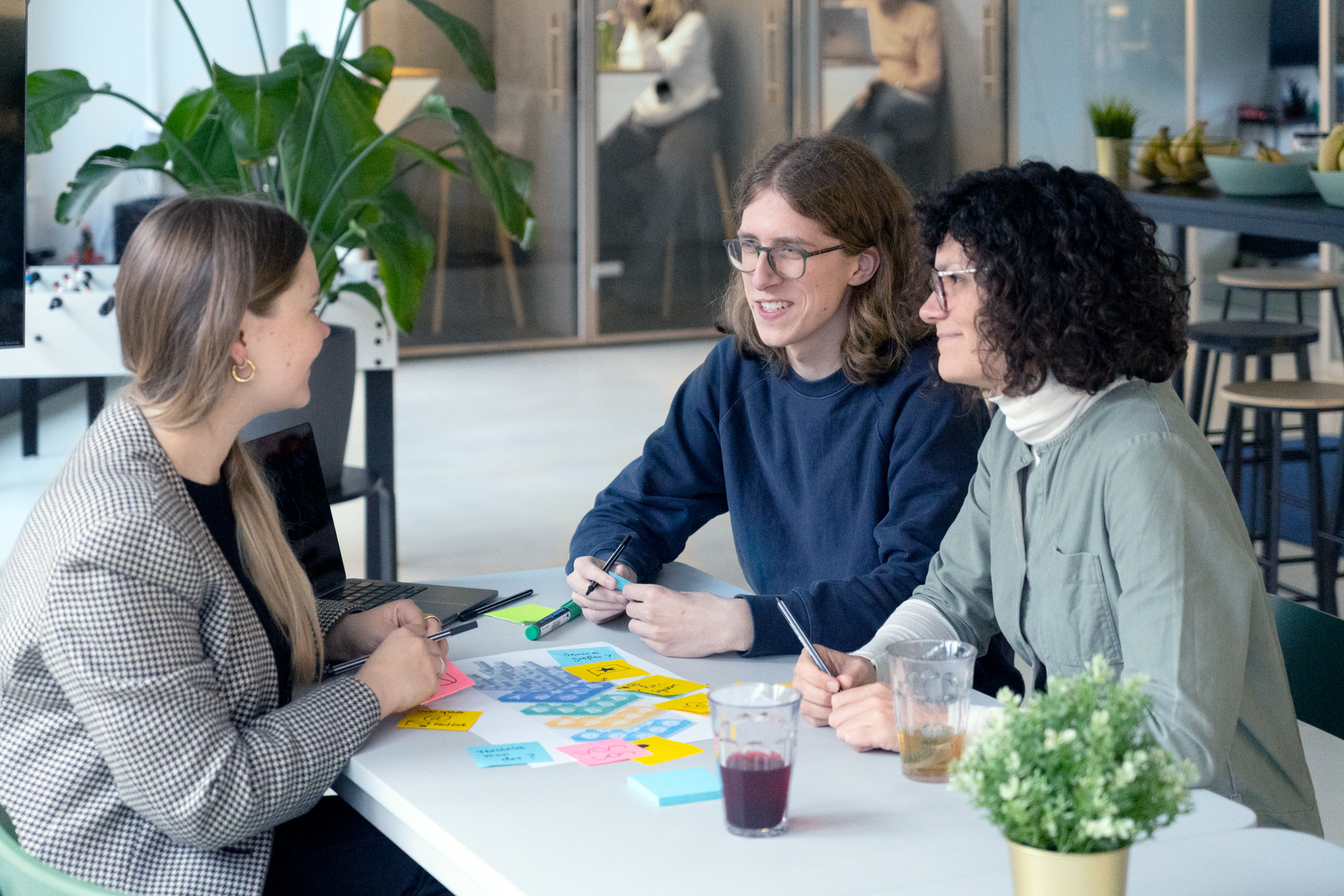 Drei Mitarbeitende des DigitalService sitzen an einem tisch zusammen und diskutieren