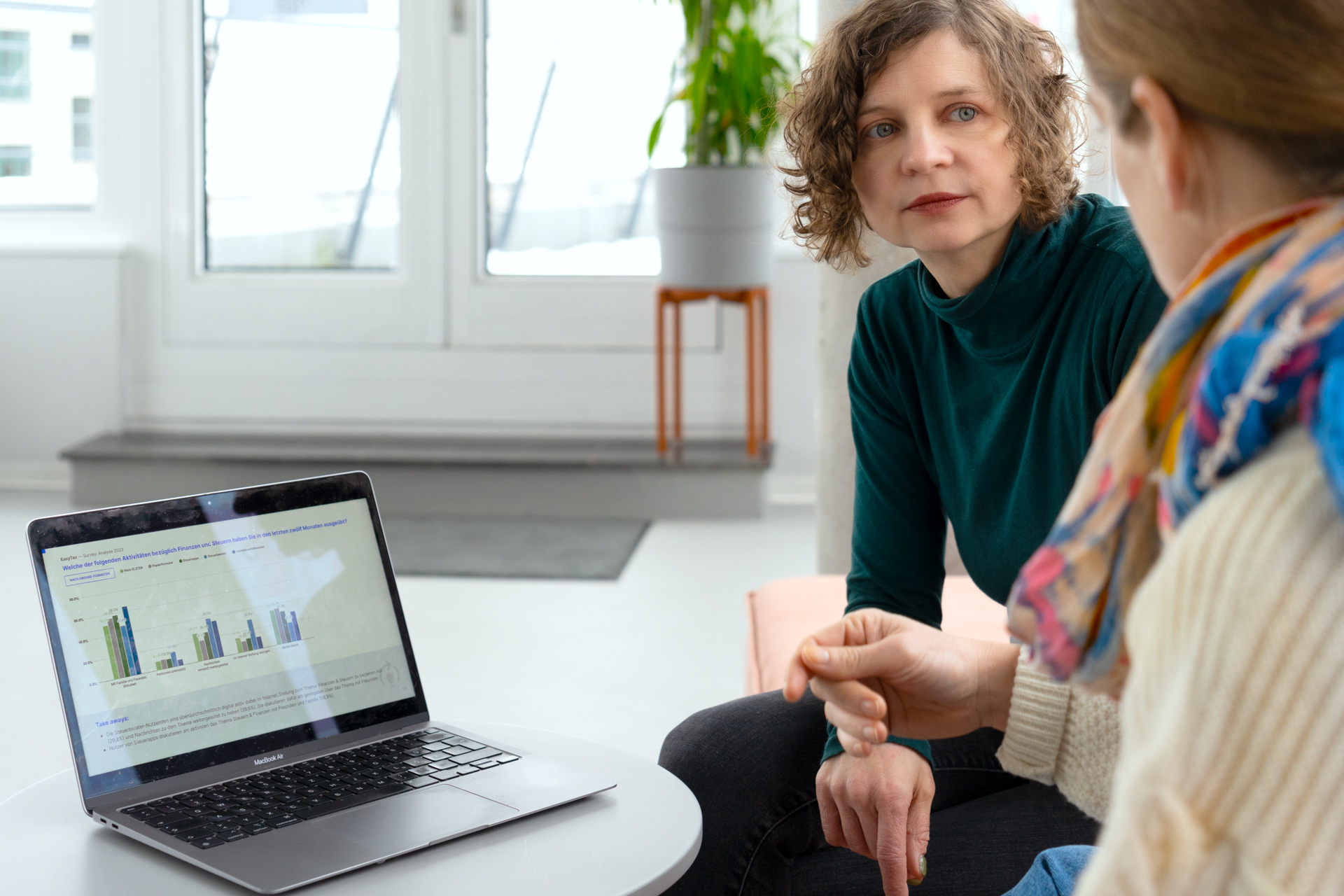 Die Autorinnen sitzen zusammen im DigitalService Büro und diskutieren über Balkendiagramme, die auf einem Laptop-Bildschirm zu sehen sind