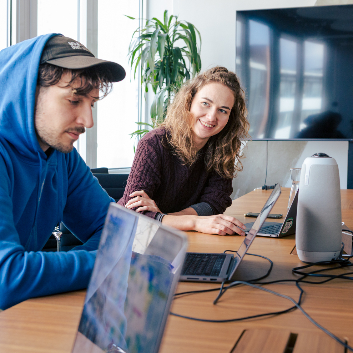 Two DigitalService employees sit at an office desk in a relaxed atmosphere and work on their laptops.