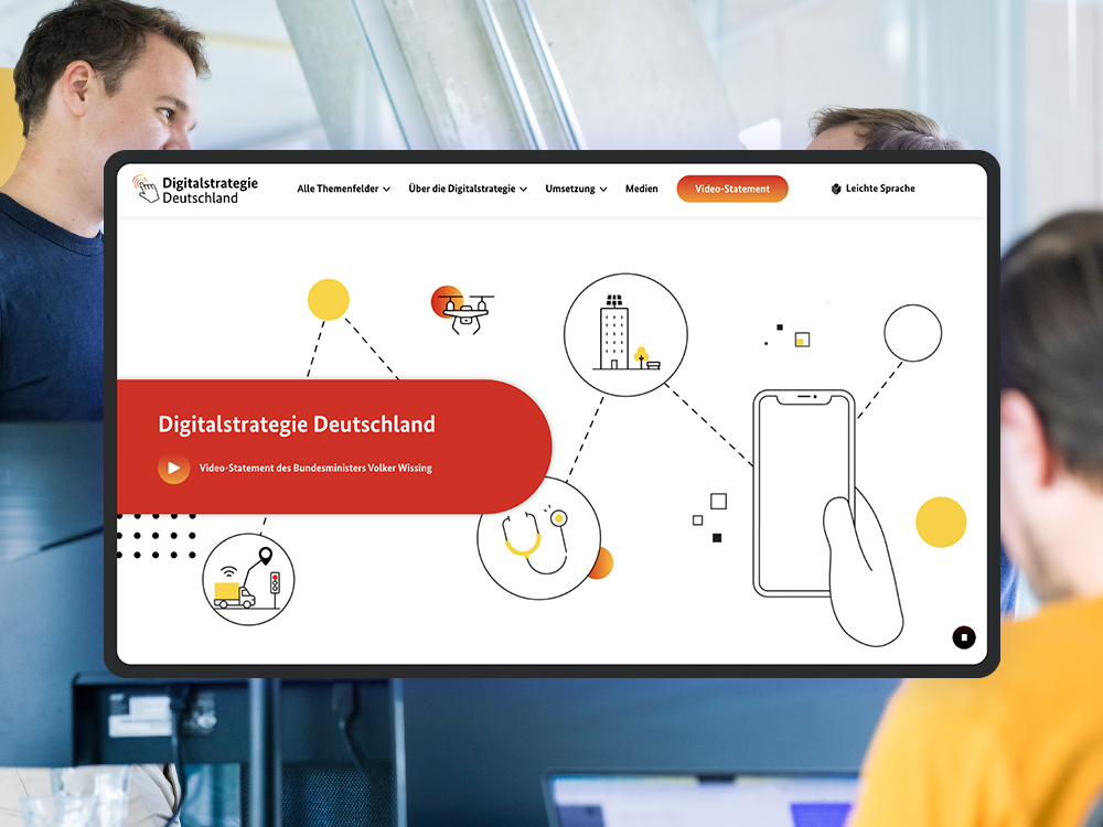 Auf einem Tablet ist die Startseite des Internettauftritts der Digitalstrategie Deutschland zu sehen; als visuelles Stilmittel sieht man im Hintergrund das Büro des DigitalService