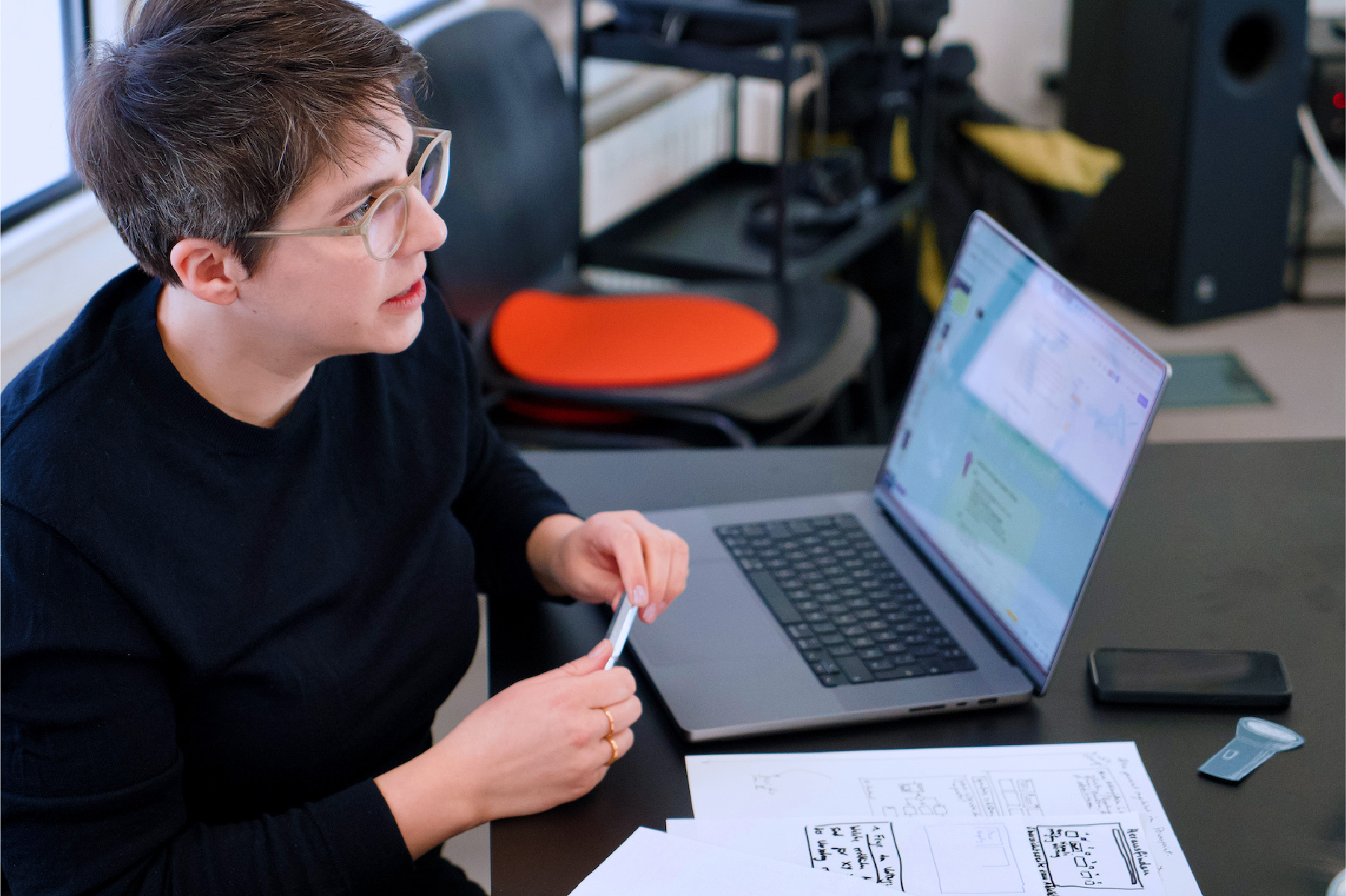 Eine Mitarbeitende des DigitalService sitzt vor ihrem aufgeklappten Laptop und macht sich Notizen auf Papierzetteln vor ihr